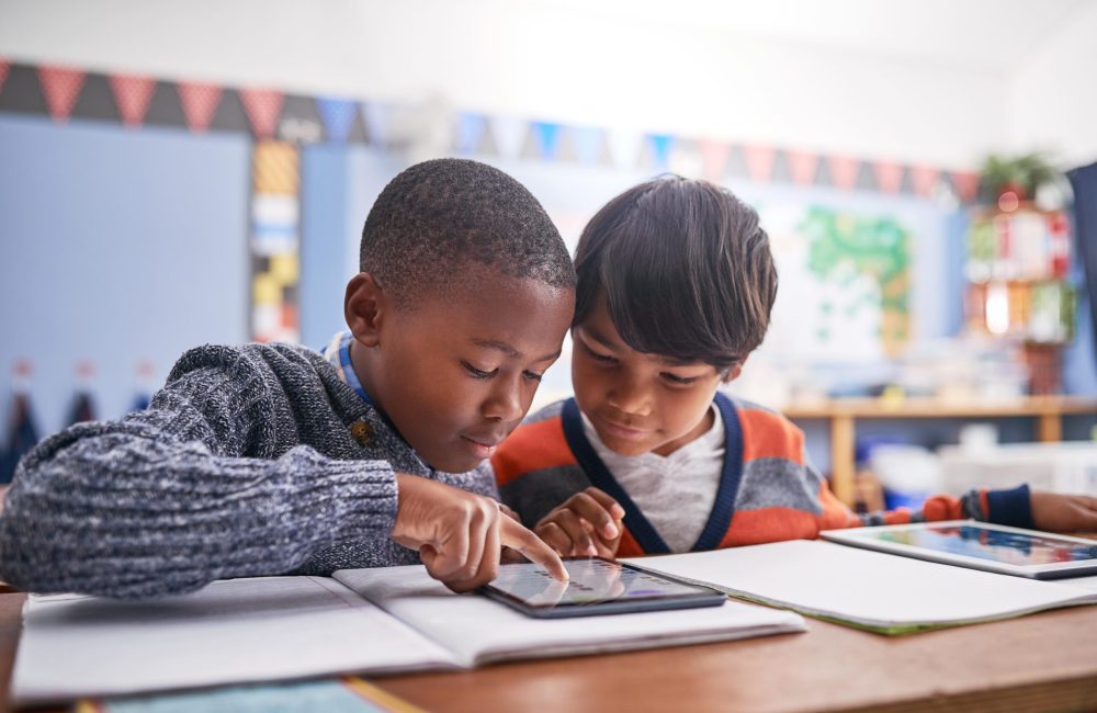 Cropped shot of elementary school children using a tablet in class